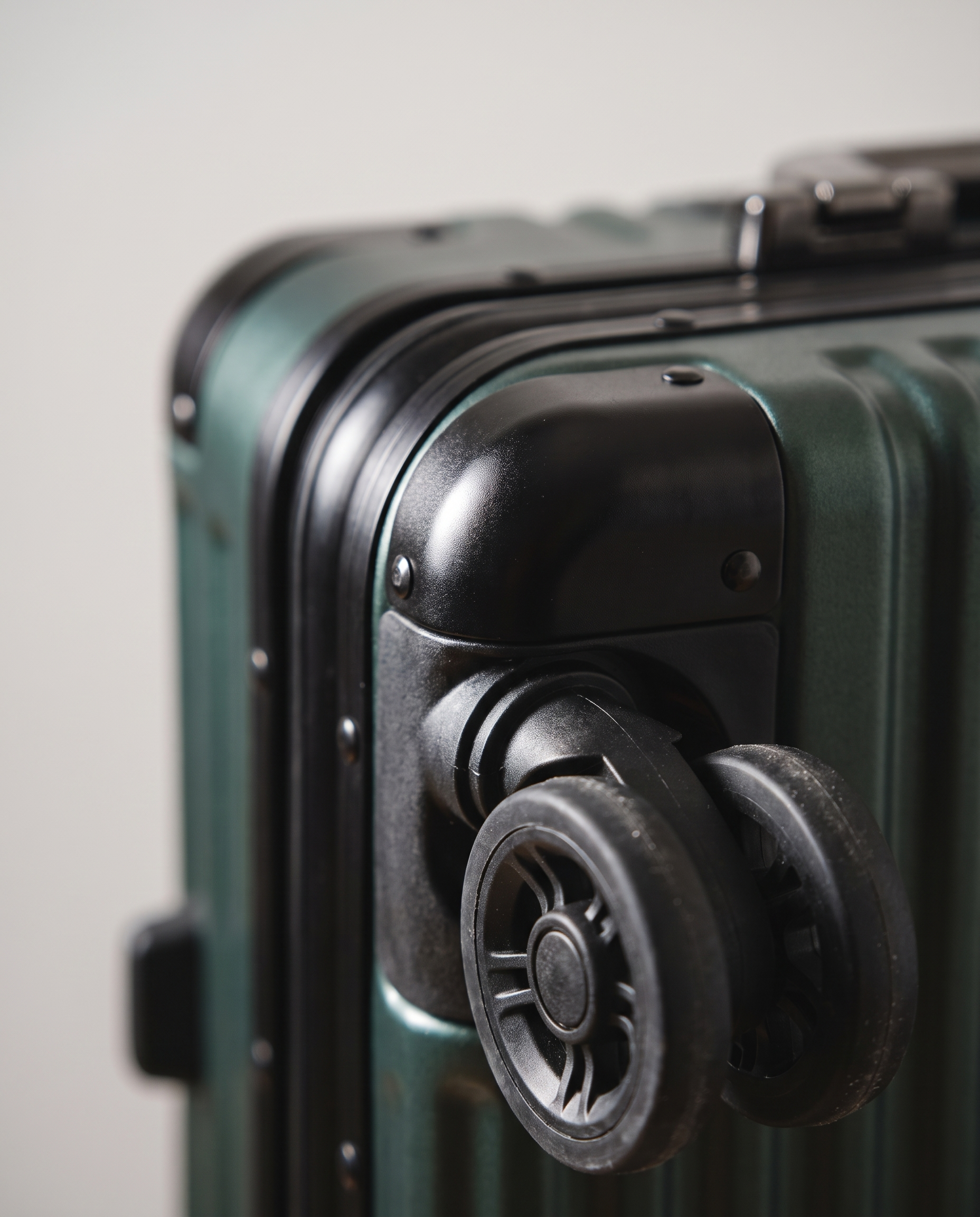 Aluminum frame suitcase in dark green — frame and wheel detail, RABUKO